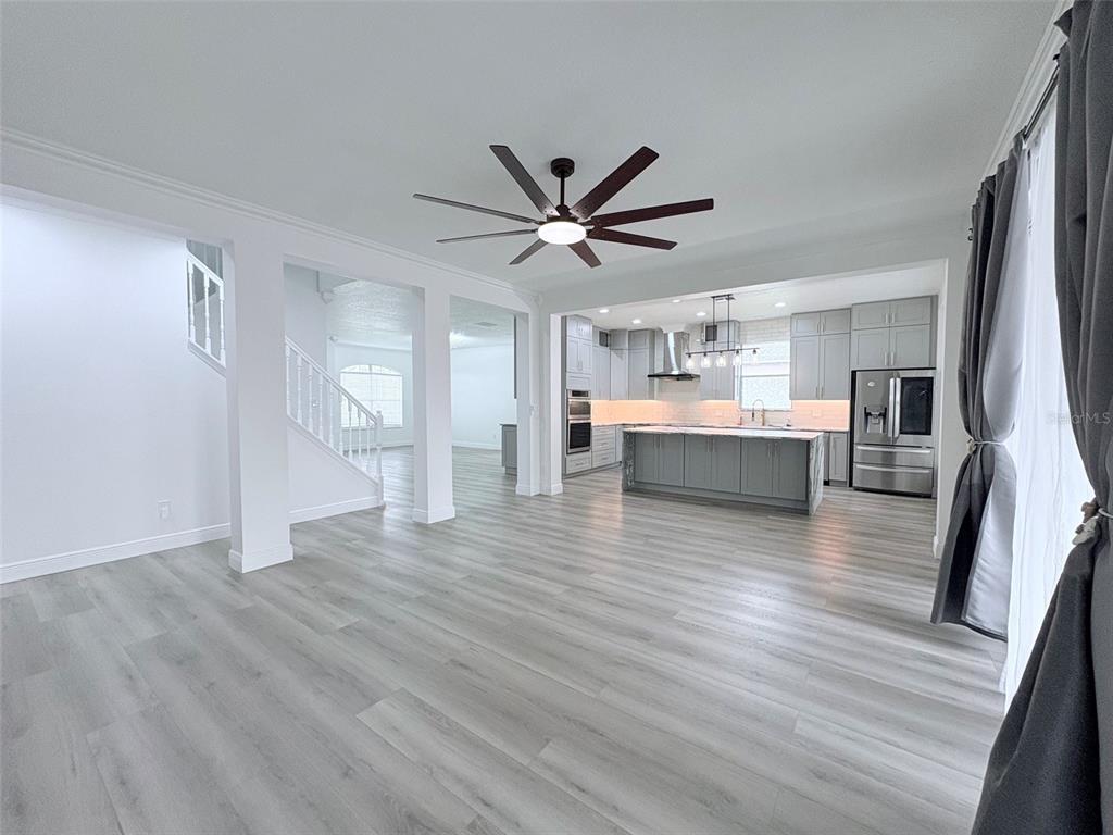 An open-concept living area features light wood-look flooring, a ceiling fan, and a modern kitchen — 2157 WINTERMERE POINTE DRIVE, WINTER GARDEN, FL