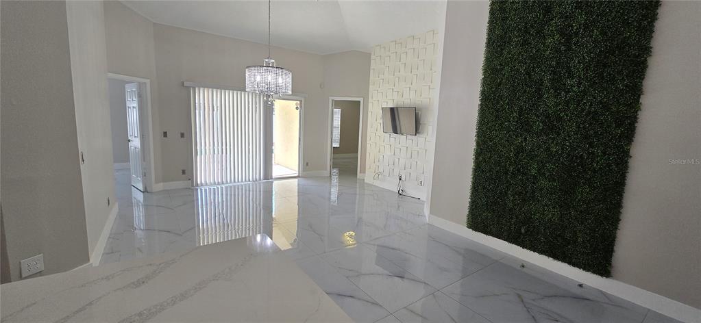 A living room features white marble-look tile flooring, a crystal chandelier, and a green wall accent — 600 ABACO COURT, KISSIMMEE, FL