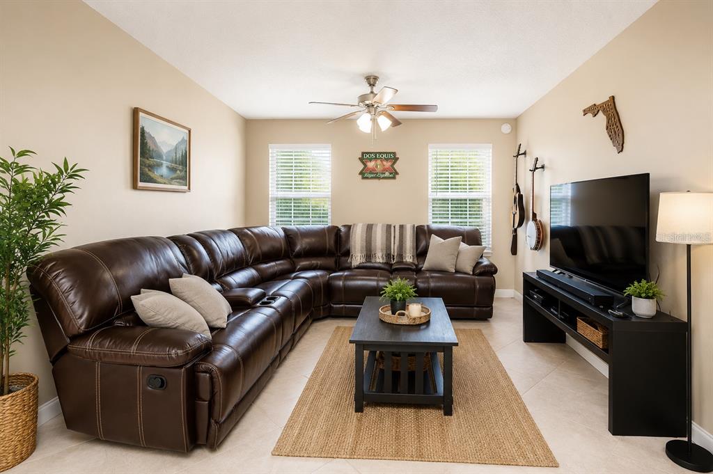 A living room features a television on a black stand, a coffee table, and tile flooring — 7504 GADSDEN DRIVE, TAMPA, FL