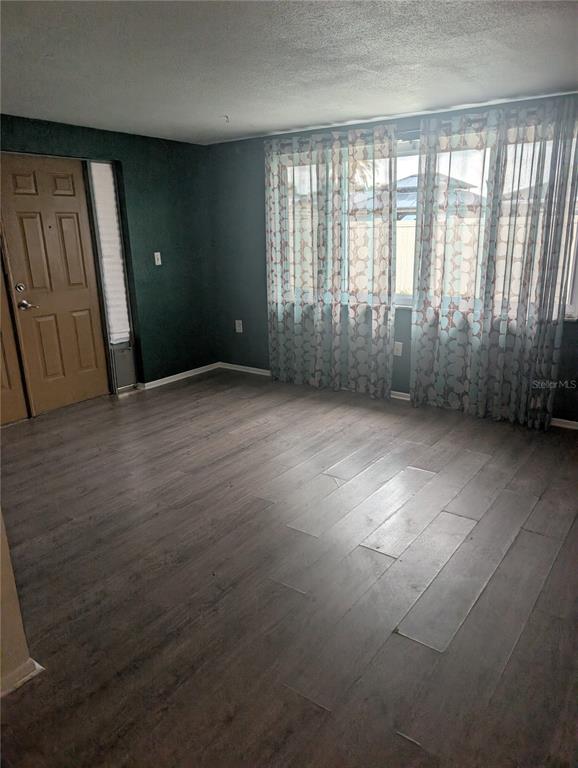 An empty room with dark green walls, wood-look flooring, and floor-to-ceiling patterned curtains — 9436 GLEN MOOR LANE, PORT RICHEY, FL