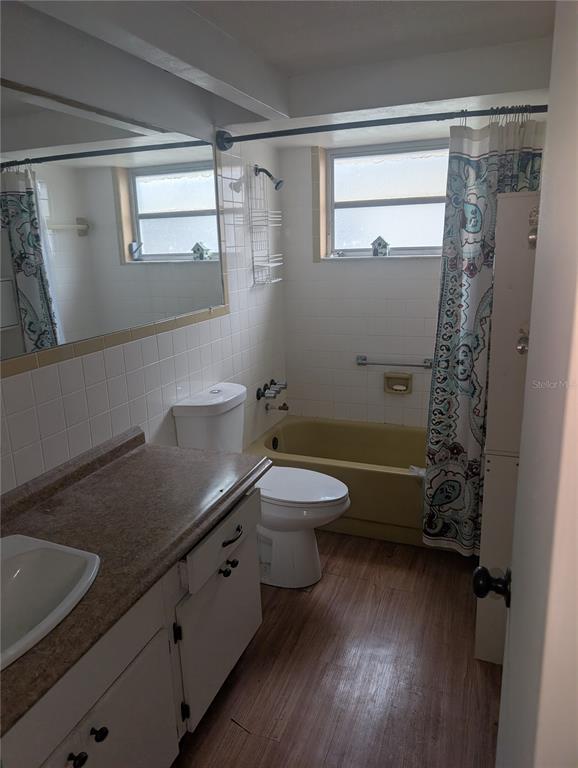 A bathroom features a vanity, a toilet, and a yellow bathtub with a shower curtain — 9436 GLEN MOOR LANE, PORT RICHEY, FL