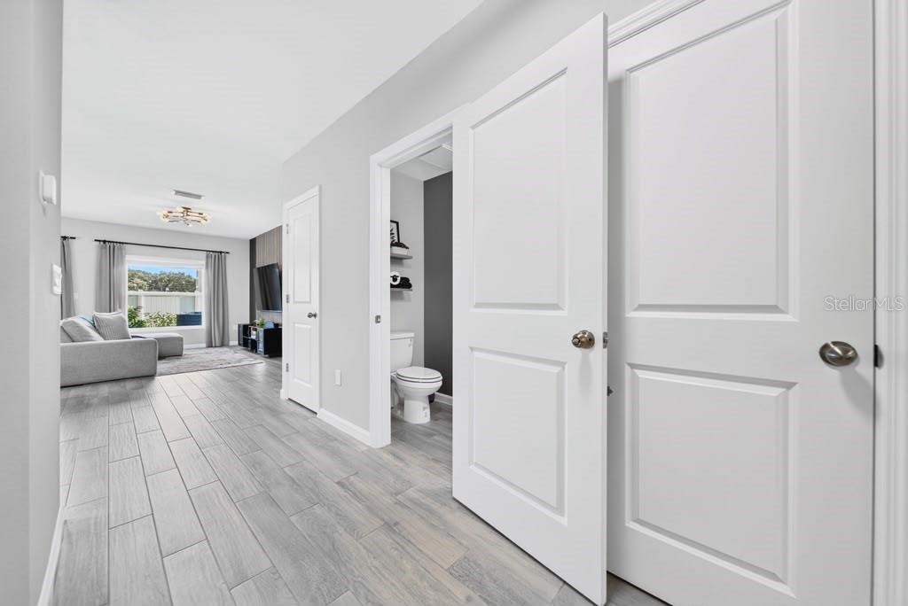 A hallway with light wood-look tile flooring leads to a living area and a bathroom — 4176 CAMPSITE LOOP, ORLANDO, FL