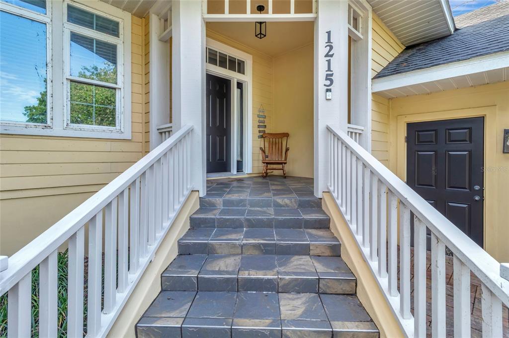A tiled staircase with white railings leads to a front porch with a wooden chair — 1215 LAKESHORE DRIVE, EUSTIS, FL