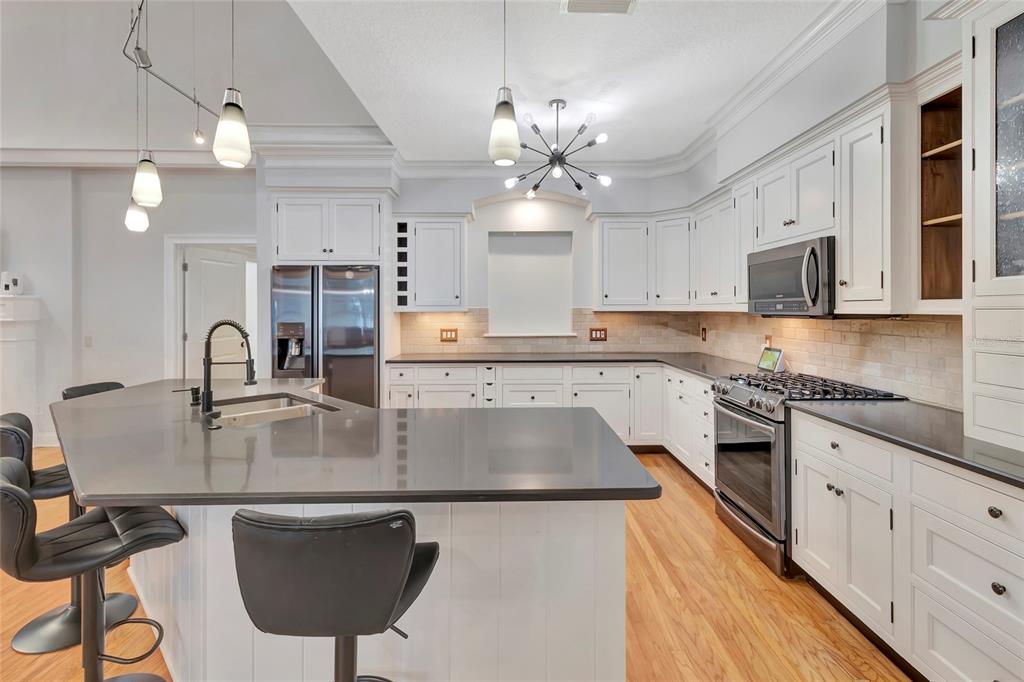 A kitchen features white cabinetry, dark countertops, a large island with bar seating, and appliances — 1215 LAKESHORE DRIVE, EUSTIS, FL