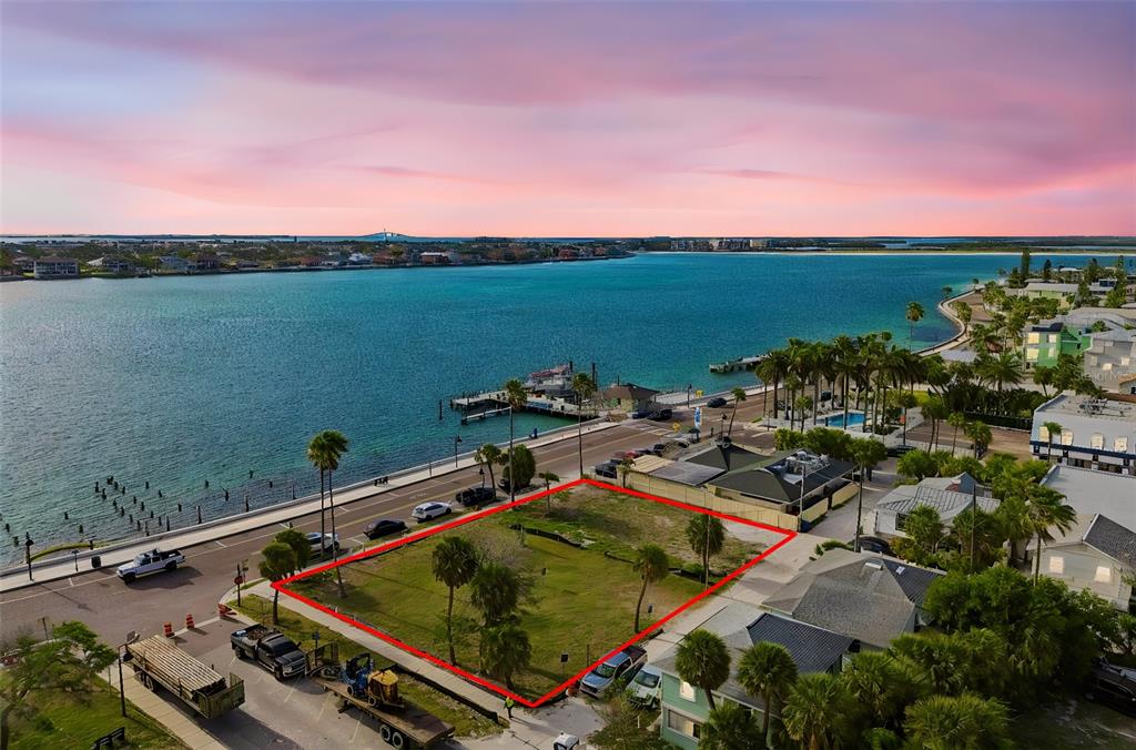 An aerial view shows a vacant rectangular waterfront lot outlined in red near a road — 808 PASS A GRILLE WAY, ST PETE BEACH, FL