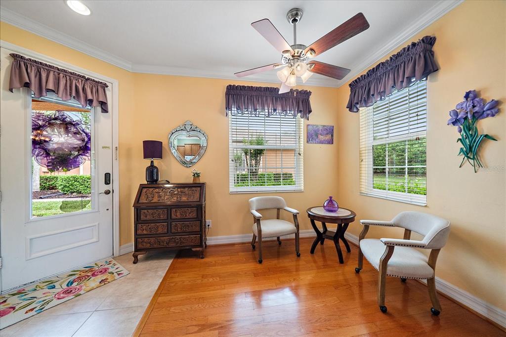 A bright foyer features hardwood floors, two armchairs, a small table, and a wooden desk — 11547 52ND COURT E, PARRISH, FL