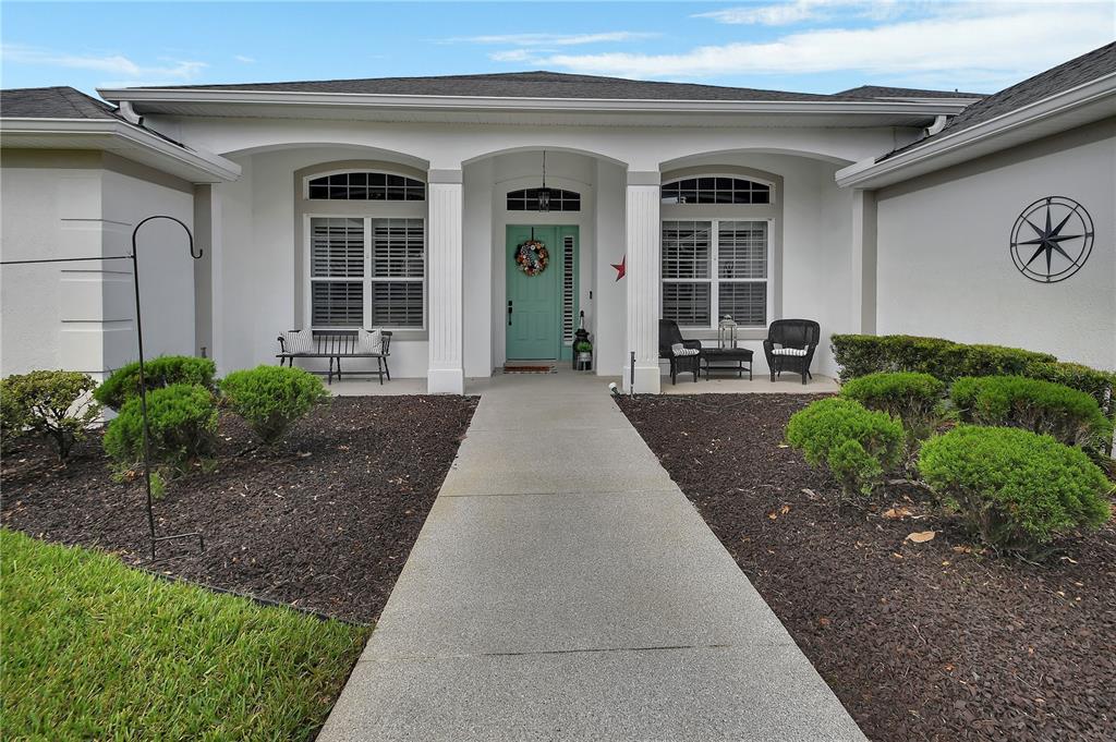 A concrete walkway leads to the front entrance of a house with a teal door — 105 PINE SIDE DRIVE, DEBARY, FL