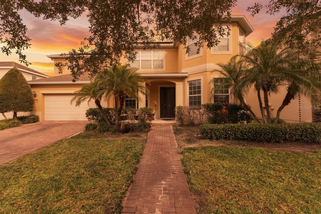 A two-story yellow stucco house with a brick walkway and a two-car garage — 13339 ROSKIN LANE, WINDERMERE, FL