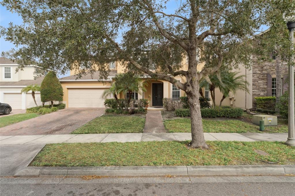 A two-story suburban house with a brick driveway, a front lawn, and a large tree — 13339 ROSKIN LANE, WINDERMERE, FL