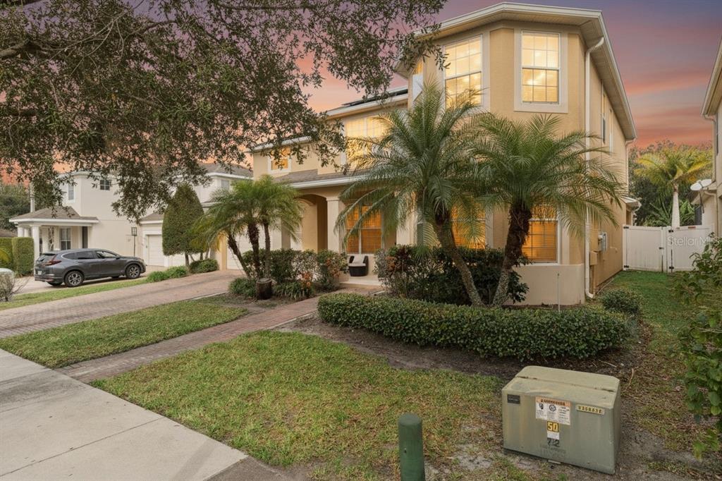 A two-story tan house with a brick walkway and palm trees in the front yard — 13339 ROSKIN LANE, WINDERMERE, FL