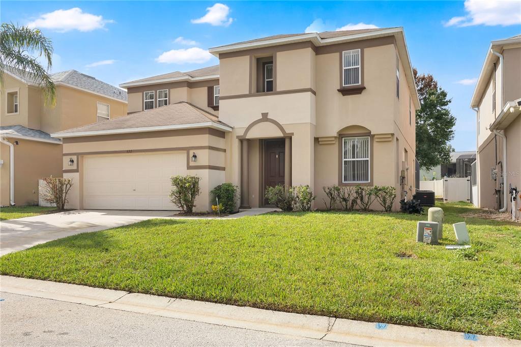 A two-story beige suburban house with a two-car garage and a front lawn — 822 KETTERING ROAD, DAVENPORT, FL