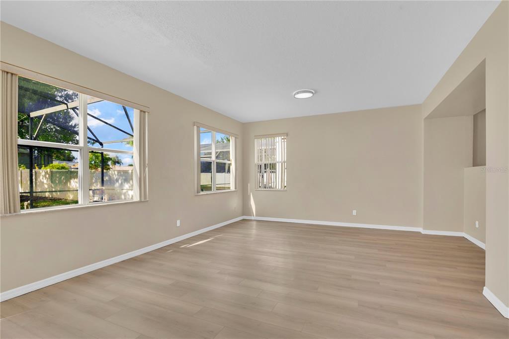 An empty room with light wood-look flooring, beige walls, and three windows — 822 KETTERING ROAD, DAVENPORT, FL