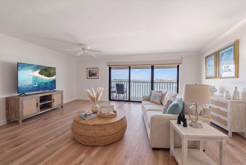 A living room features light wood flooring, a beige sofa, and a balcony overlooking water — 55 ROGERS STREET UNIT P3, CLEARWATER, FL