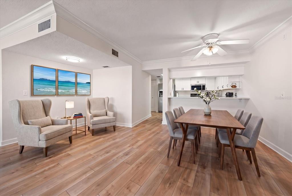 A dining area and seating space with light wood floors, white walls, and a kitchen pass-through — 55 ROGERS STREET UNIT P3, CLEARWATER, FL
