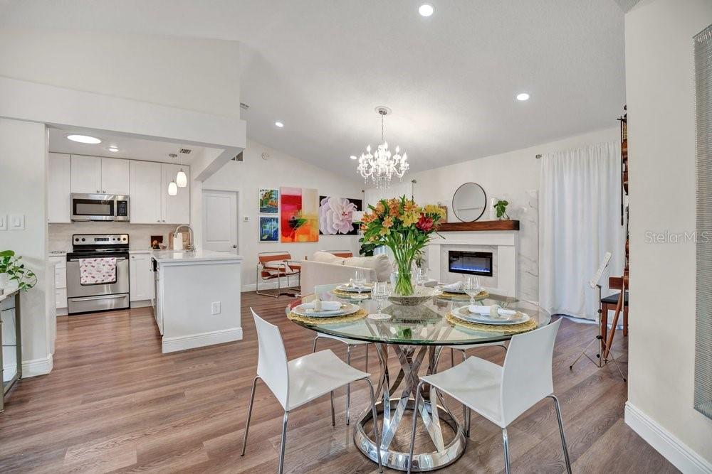 A dining area with a glass table sits in front of an open-concept kitchen and fireplace — 2958 MALLORN WAY, CASSELBERRY, FL