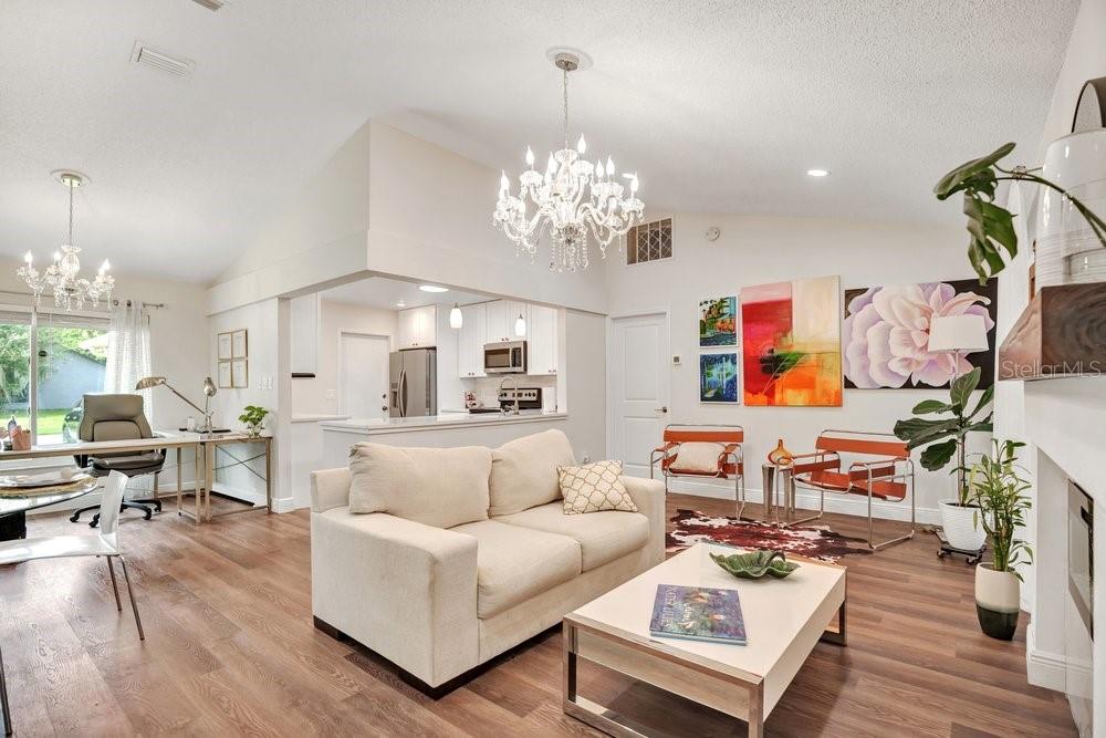 A living room with wood floors, a beige sofa, two orange chairs, and a chandelier — 2958 MALLORN WAY, CASSELBERRY, FL