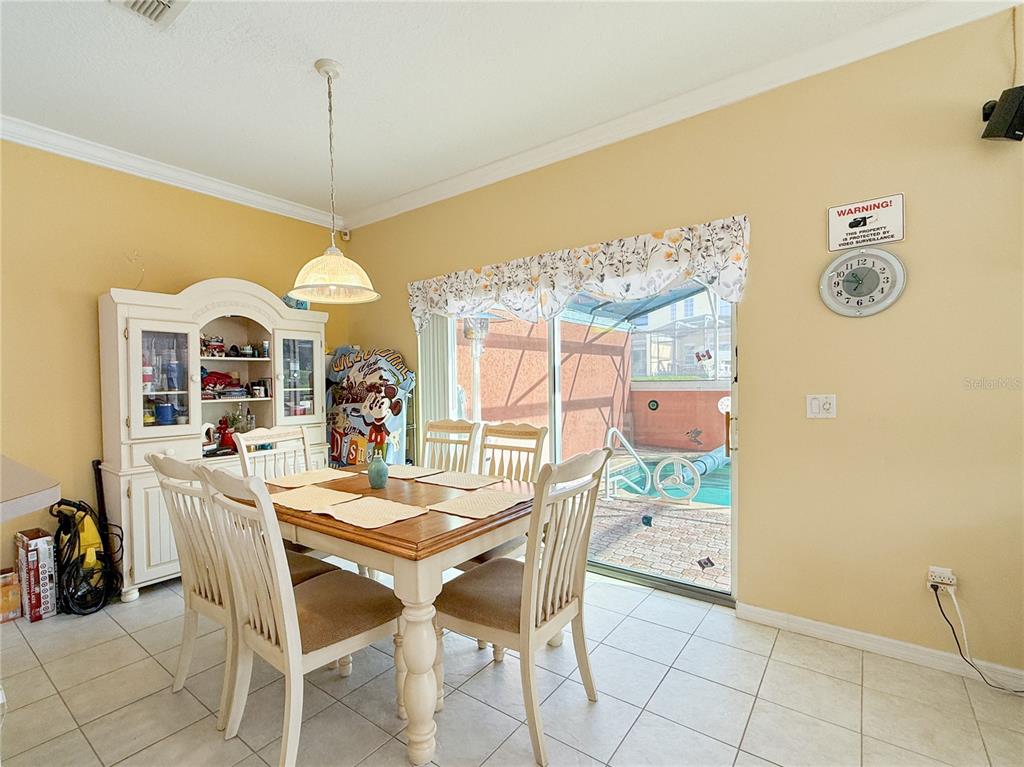 A dining room features a wooden table, white chairs, a hutch, and a sliding glass door — 8535 BAY LILLY LOOP, KISSIMMEE, FL