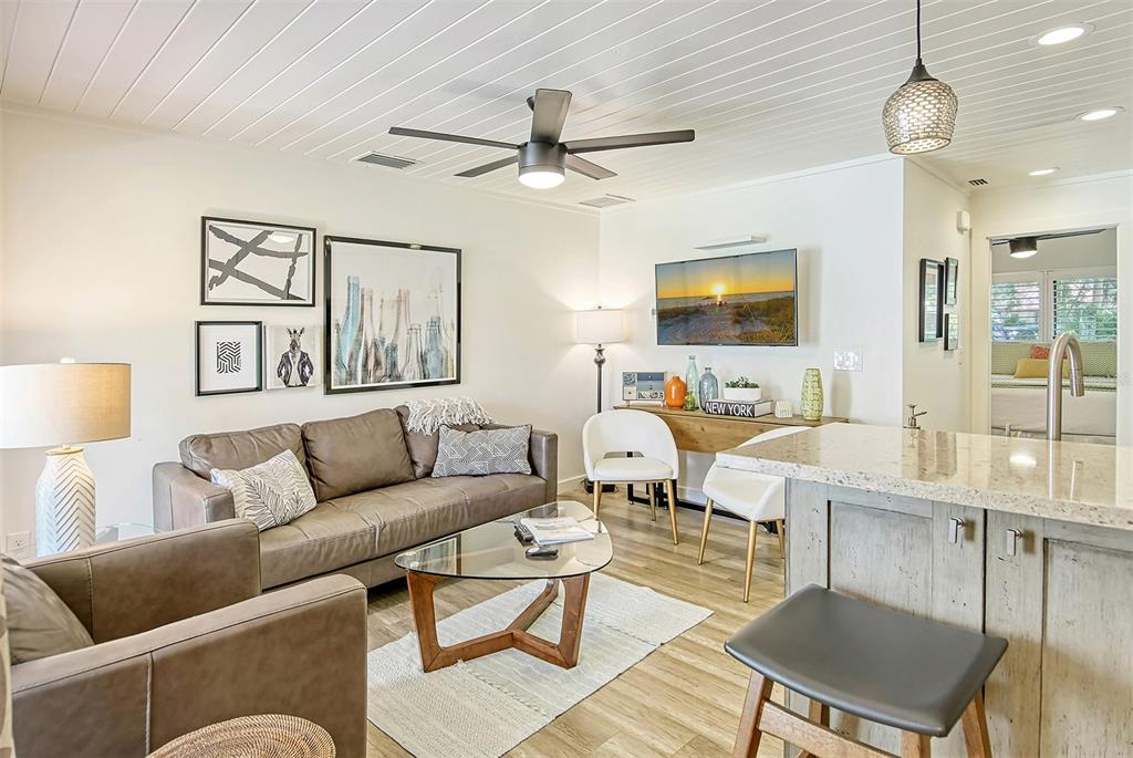 A living room features a leather sofa, glass coffee table, and open kitchen island — 3545 LONGMEADOW UNIT 23, SARASOTA, FL