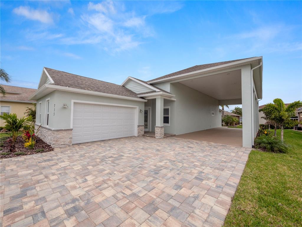 A light green house with a stone-accented garage and a large covered side carport — 715 TEABERRY TRAIL, POLK CITY, FL