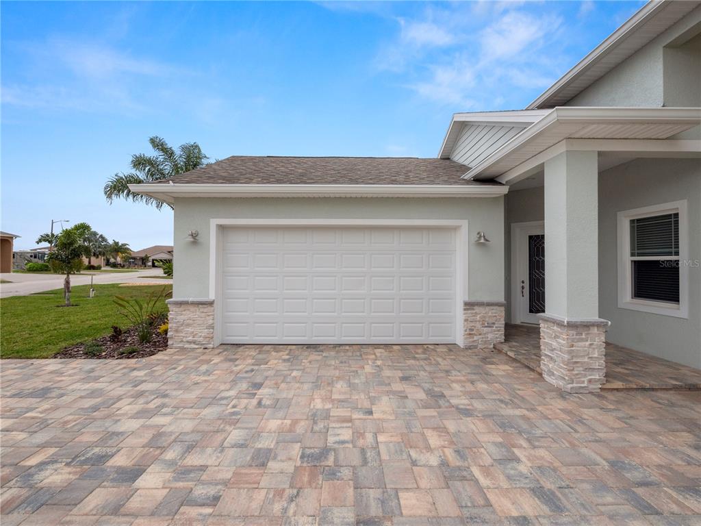 A house exterior features a paved driveway, a white garage door, and stone accents — 715 TEABERRY TRAIL, POLK CITY, FL