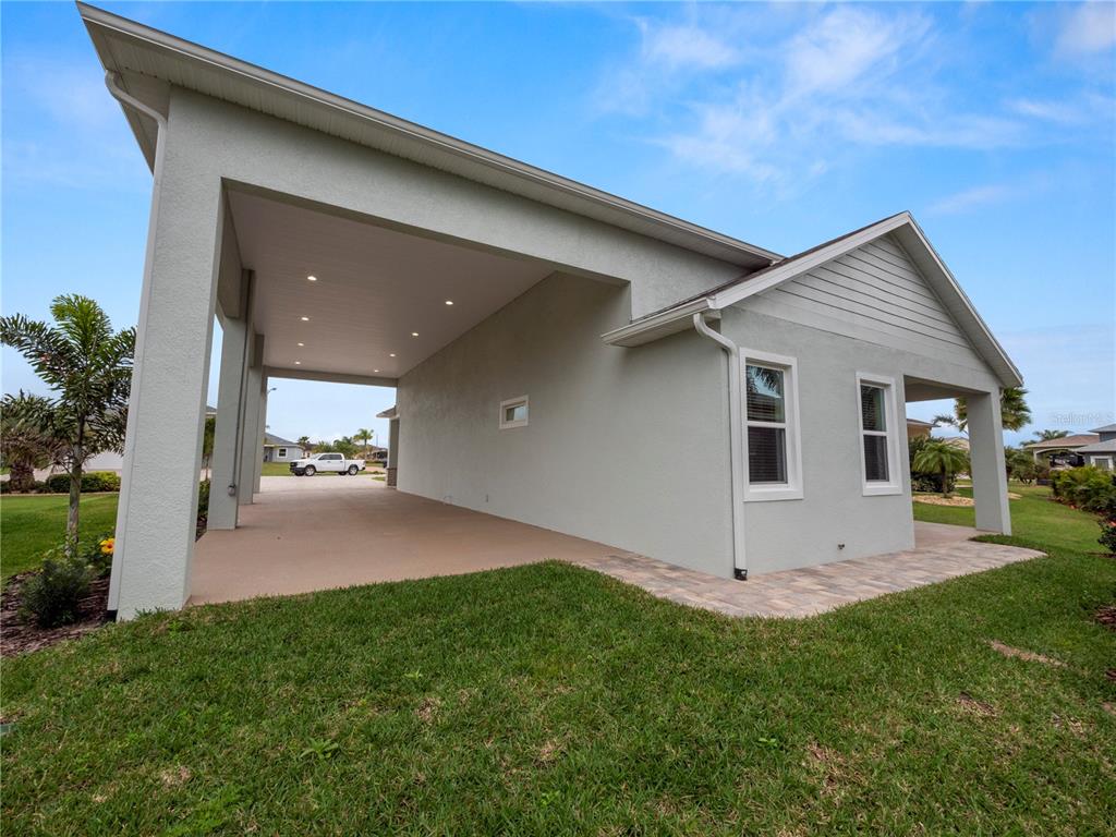 A light-colored house exterior features a large covered carport and a paved walkway — 715 TEABERRY TRAIL, POLK CITY, FL