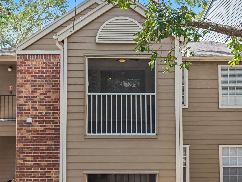 The exterior of a multi-story building features tan siding, a brick facade, and a screened balcony — 5112 PARK CENTRAL DRIVE UNIT 621, ORLANDO, FL