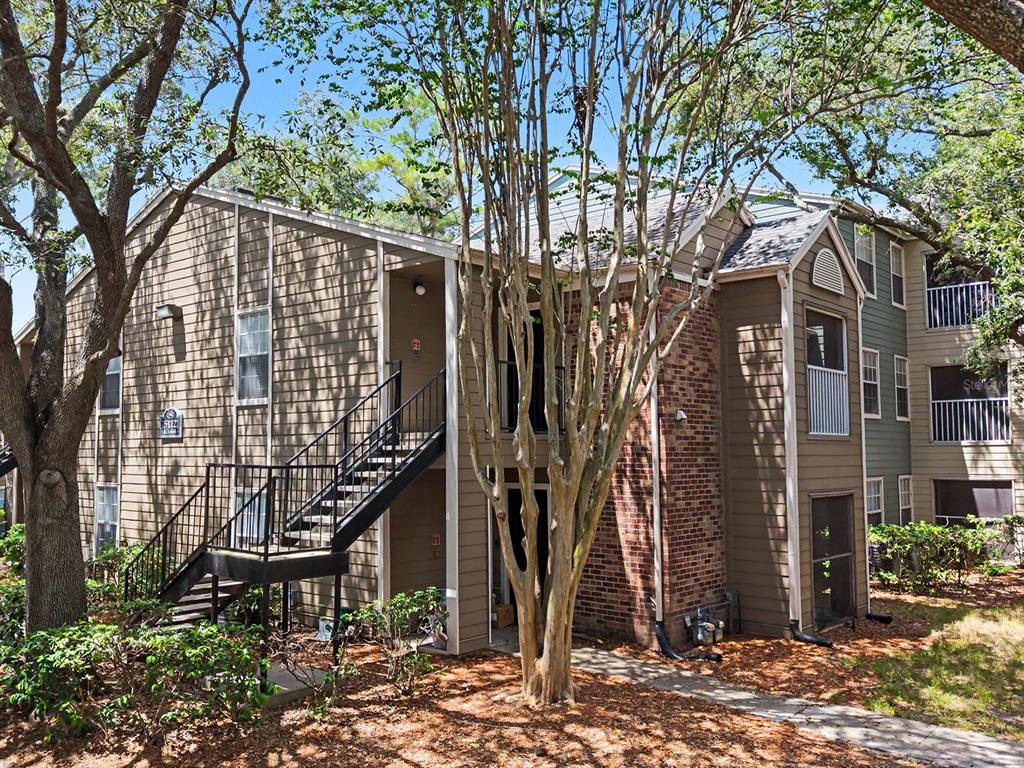 A two-story apartment building with tan siding, brick accents, and an exterior metal staircase — 5112 PARK CENTRAL DRIVE UNIT 621, ORLANDO, FL