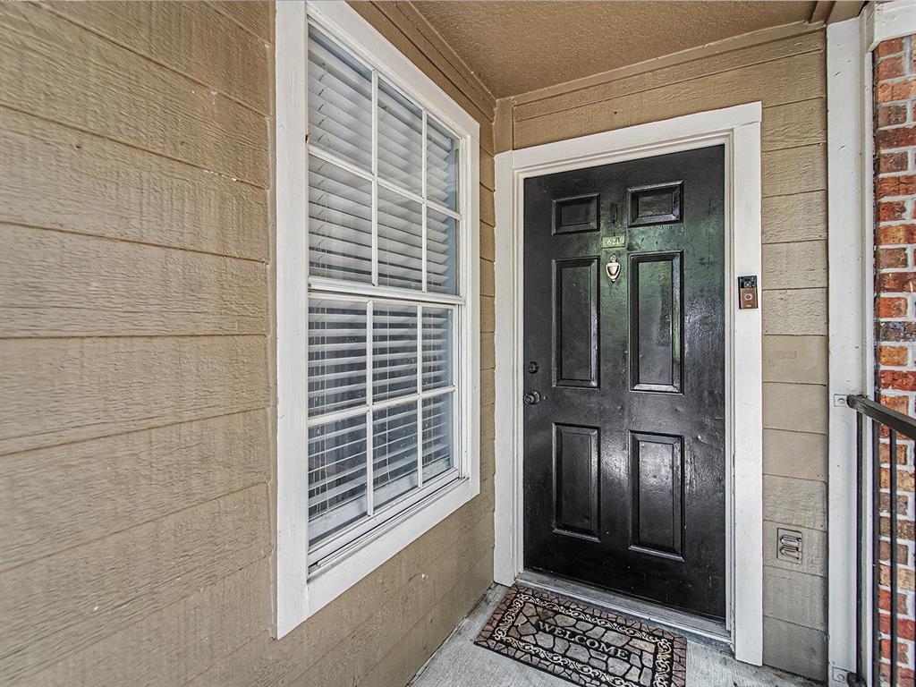 A black front door with a window and welcome mat on a tan exterior wall — 5112 PARK CENTRAL DRIVE UNIT 621, ORLANDO, FL