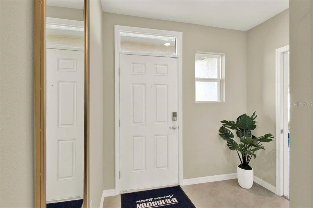 This entryway features a white front door, a tall floor mirror, and a potted plant — 4160 GIORGIO DRIVE, WINTER HAVEN, FL