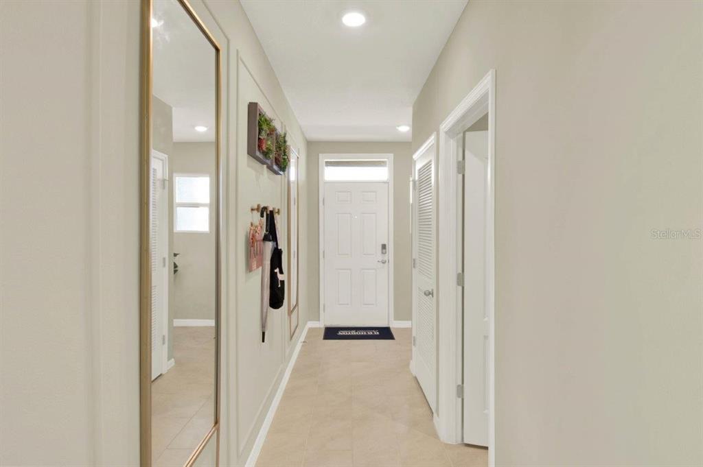 A bright entryway features a long mirror, wall decor, and a white front door — 4160 GIORGIO DRIVE, WINTER HAVEN, FL