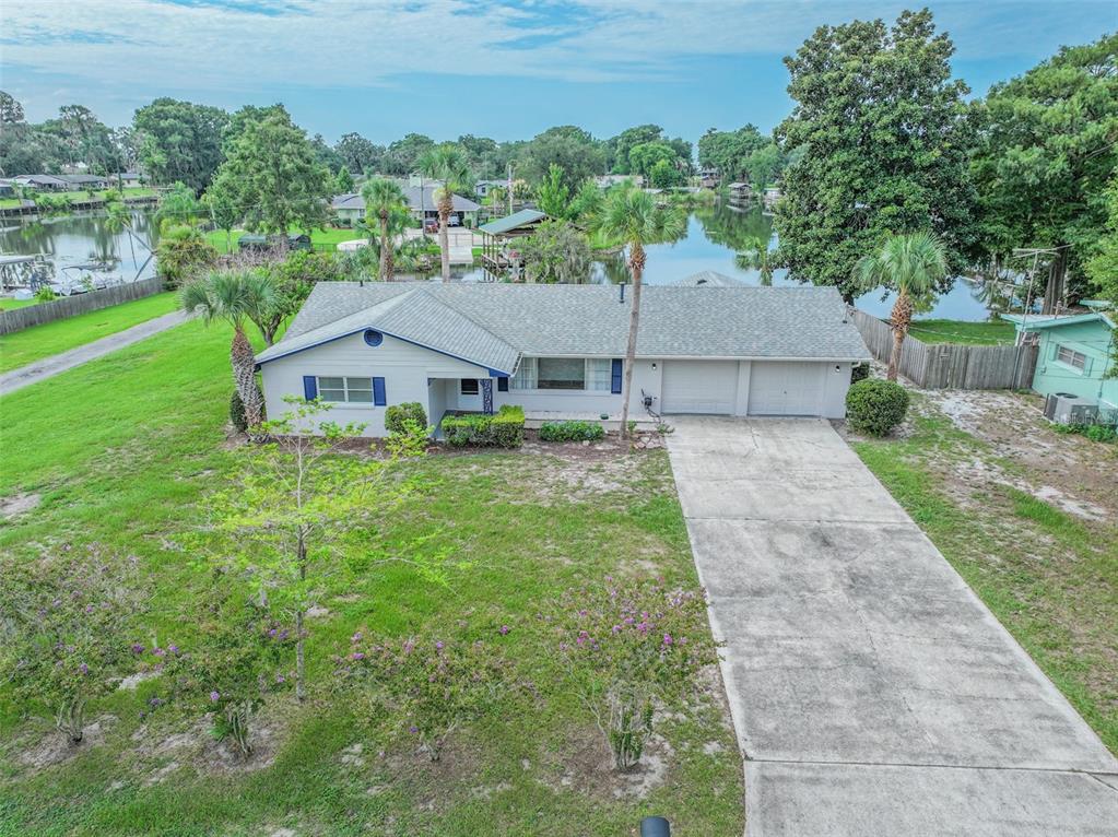 An aerial view of a single-story house with a concrete driveway and a waterfront backyard — 2712 GRAND ISLAND SHORES ROAD, EUSTIS, FL