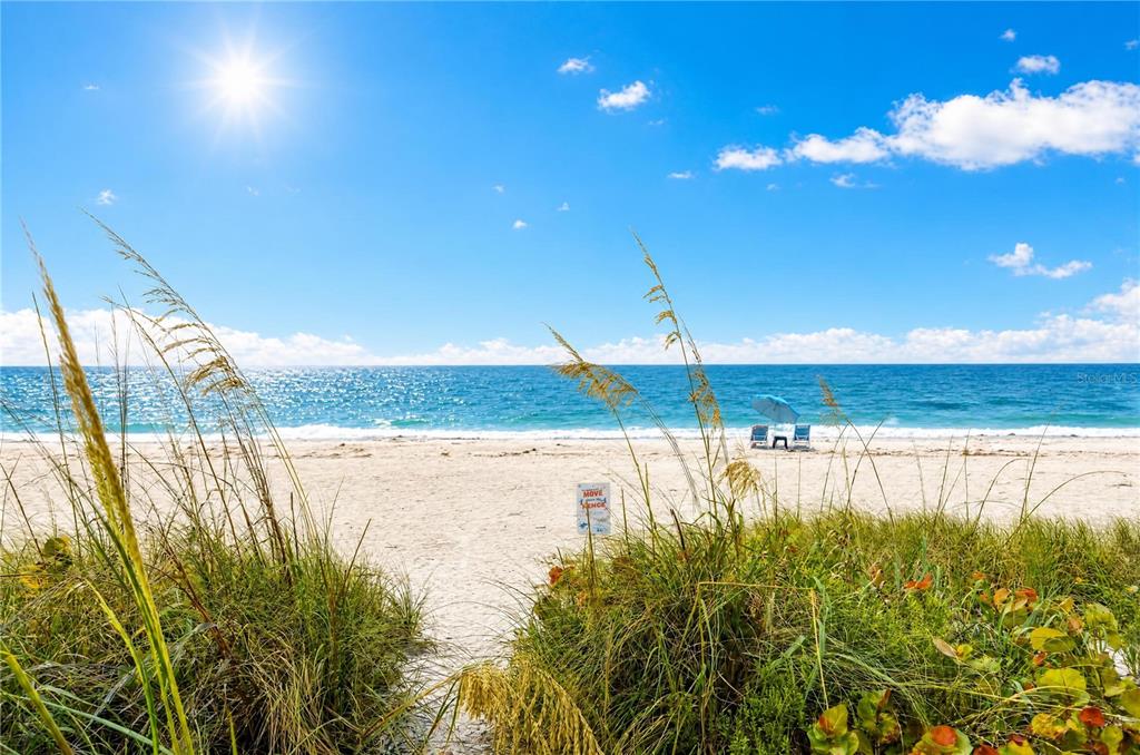 A sandy beach path leads through sea oats toward the ocean under a sunny sky — 5275 GULF OF MEXICO DRIVE UNIT 202, LONGBOAT KEY, FL