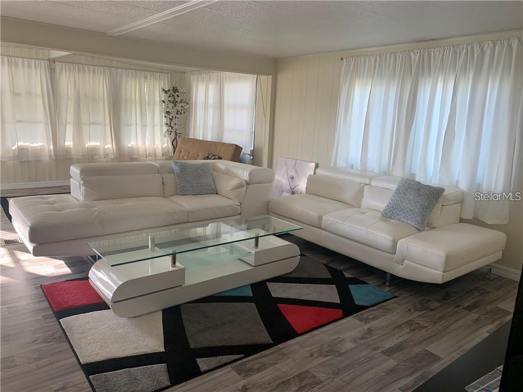 A living room features two white leather sofas, a glass coffee table, and a geometric rug — 10 BOCA CIEGA, NOKOMIS, FL