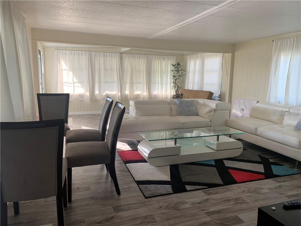 A living and dining area features white leather sofas, a glass coffee table, and wood-look flooring — 10 BOCA CIEGA, NOKOMIS, FL