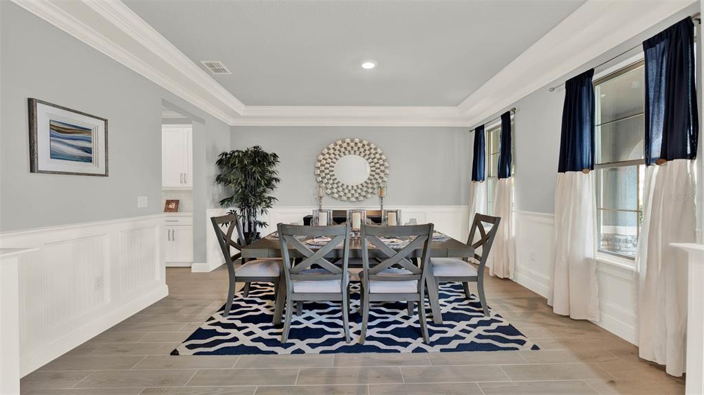 A dining room features a wooden table, six chairs, a patterned rug, and wainscoting — 11845 SHINE VIEW LANE, WINTER GARDEN, FL