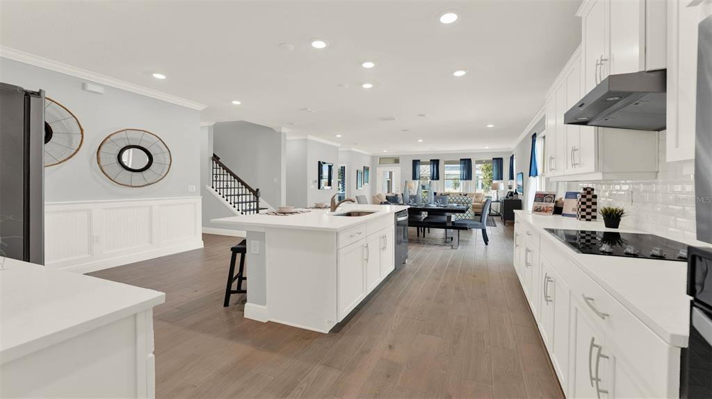 A bright, open-concept kitchen features white cabinetry, a large center island, and wood-look flooring — 11845 SHINE VIEW LANE, WINTER GARDEN, FL
