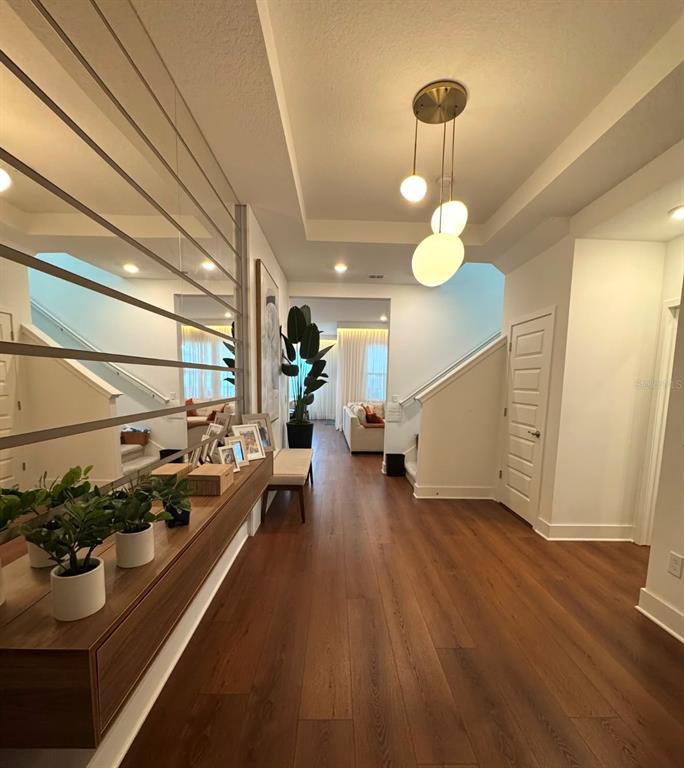 A bright entryway features wood floors, a modern pendant light, and a large wall mirror — 14931 LEBEAU LOOP, WINTER GARDEN, FL