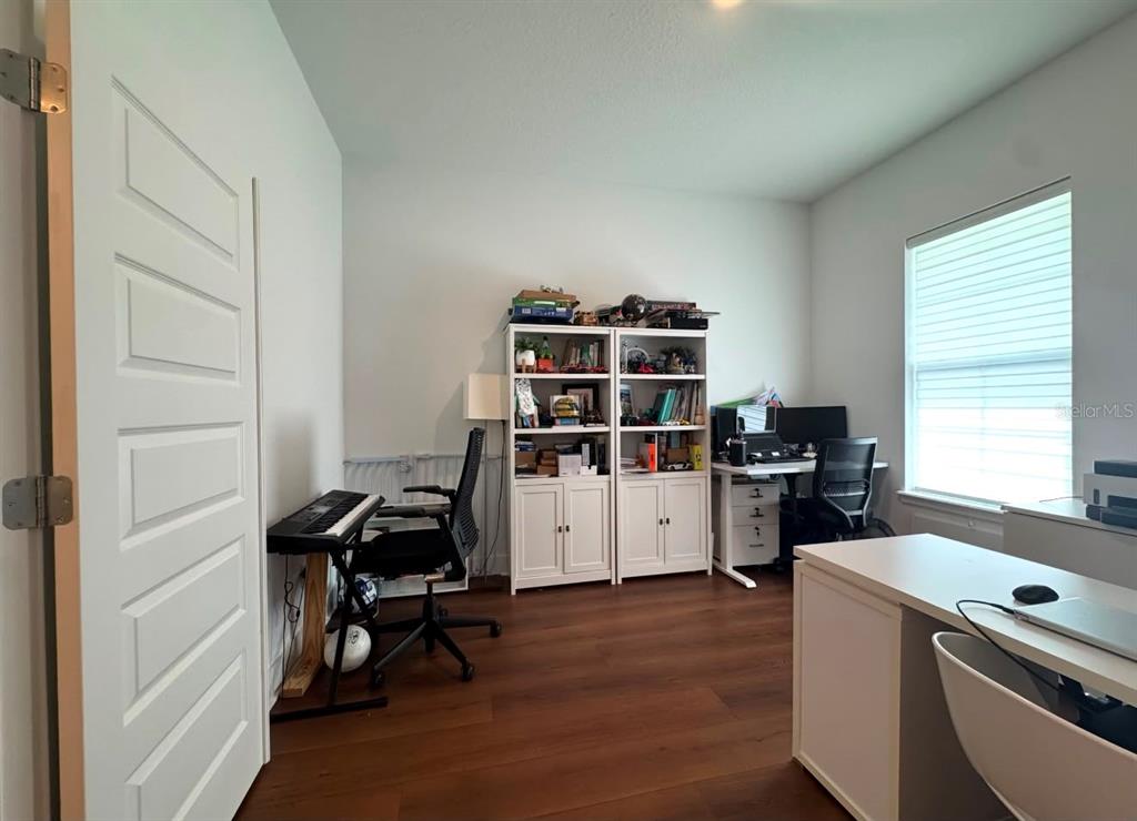 This home office features wood-look flooring, two white bookcases, and two desks — 14931 LEBEAU LOOP, WINTER GARDEN, FL