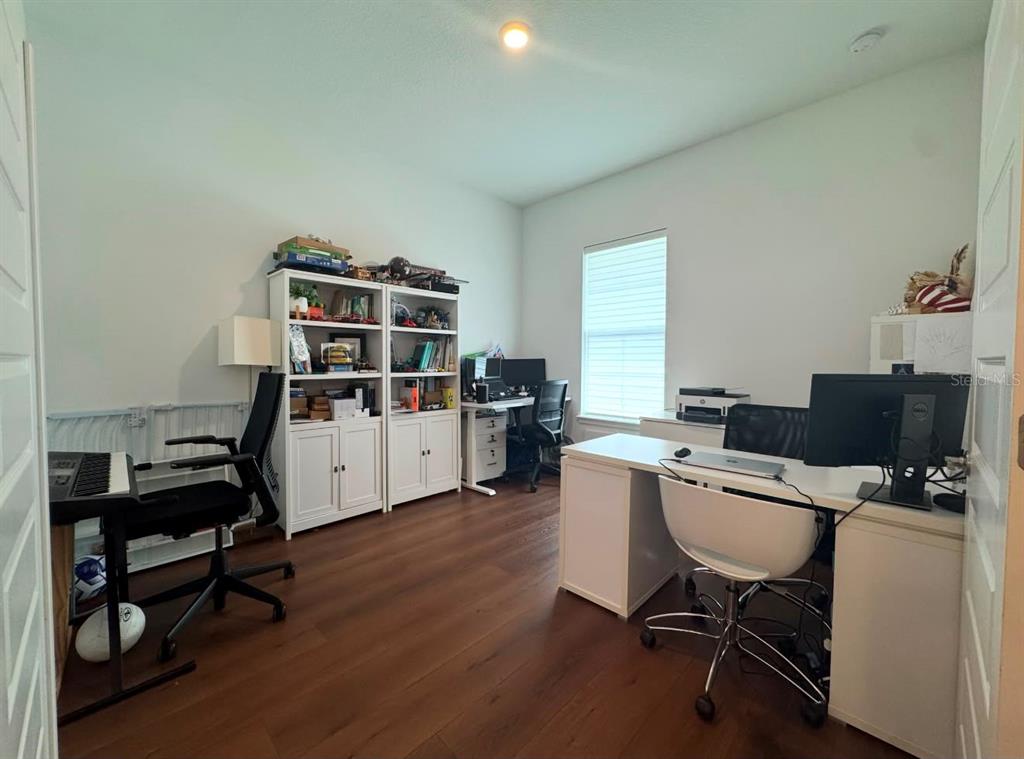 A home office features wood-look flooring, two white bookcases, and two desks with chairs — 14931 LEBEAU LOOP, WINTER GARDEN, FL
