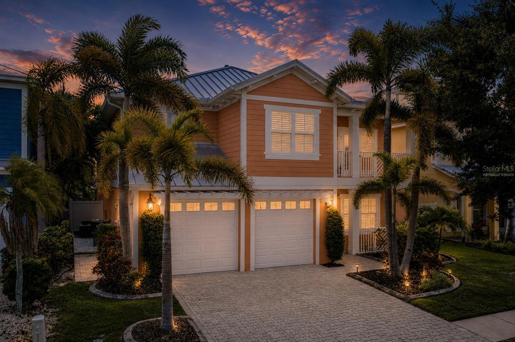 A two-story orange house with a metal roof, two garage doors, and palm trees — 6411 GRENADA ISLAND AVENUE, APOLLO BEACH, FL