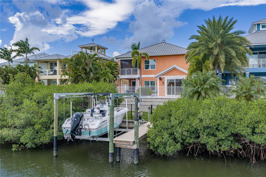 A boat on a lift sits in a canal in front of a two-story house — 6411 GRENADA ISLAND AVENUE, APOLLO BEACH, FL