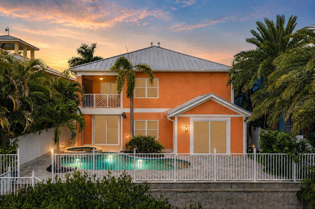 The exterior of an orange two-story house features a swimming pool, spa, and palm trees — 6411 GRENADA ISLAND AVENUE, APOLLO BEACH, FL