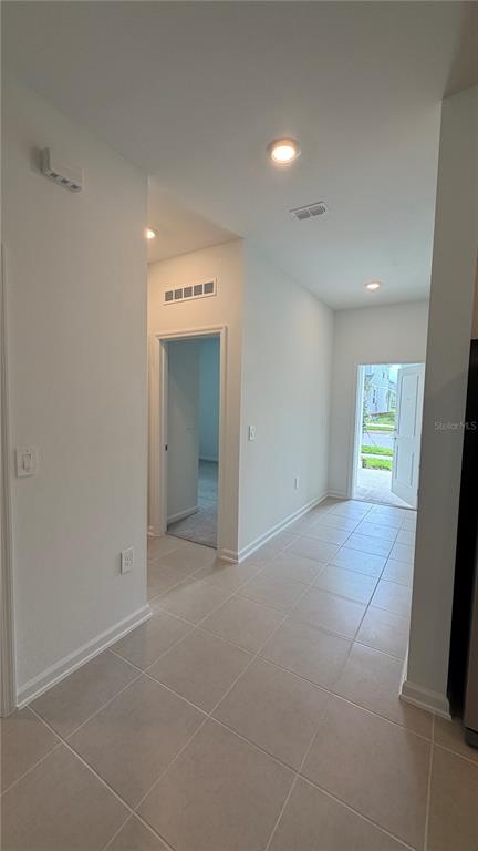 A tiled hallway leads to an open doorway and a front entrance with light walls — 6044 MEDITATION DRIVE, CLERMONT, FL