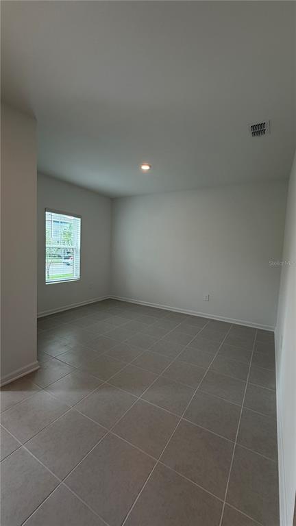 An empty room with light-colored walls, large square floor tiles, and a single window — 6044 MEDITATION DRIVE, CLERMONT, FL