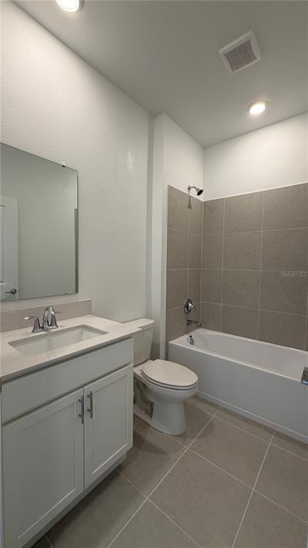 A bathroom features a white vanity, a toilet, and a bathtub with gray tiled walls — 6044 MEDITATION DRIVE, CLERMONT, FL