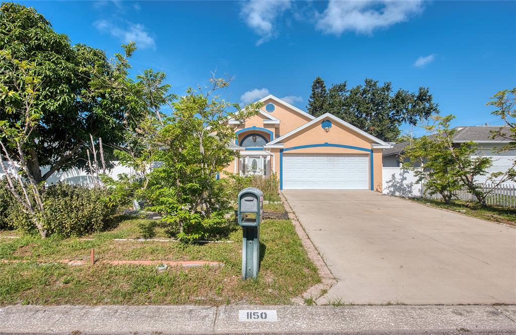 A two-story house with a peach exterior, a two-car garage, and a front yard — 1150 OAKWOOD DRIVE, DUNEDIN, FL