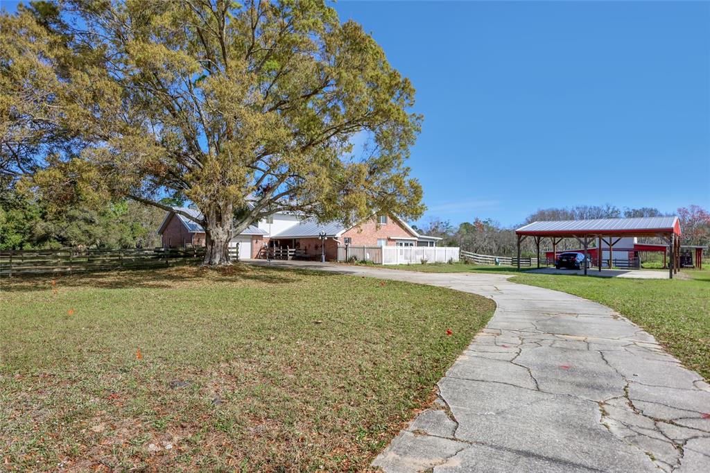A brick house with a large tree and a detached carport sits on a grassy lot — 5005 HIGHWAY 1, MIMS, FL