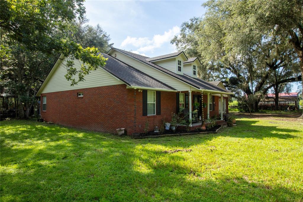 A two-story house with a brick lower level, beige siding, and a covered front porch — 9284 NW CR  225, STARKE, FL