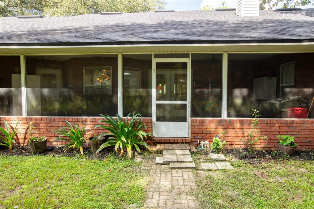 A brick house features a screened-in porch with a central door and a stone walkway — 9284 NW CR  225, STARKE, FL