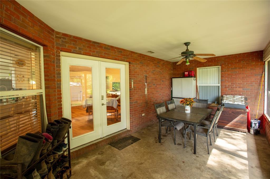 A covered brick patio features a dining set, a ceiling fan, and a shoe rack — 9284 NW CR  225, STARKE, FL